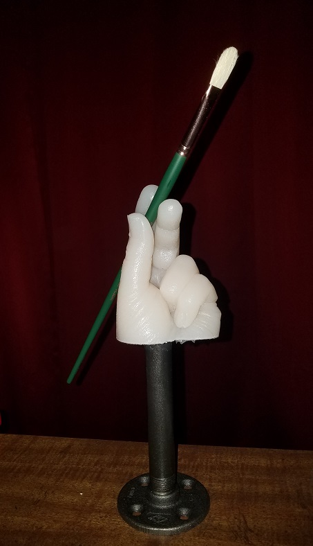 lifecast of hand on metal stand holding a paintbrush