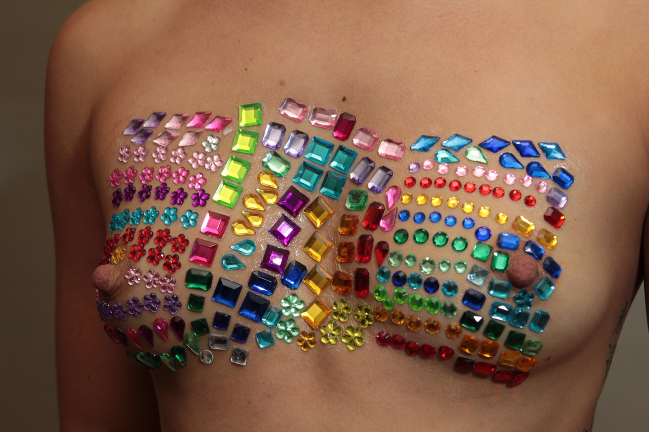 Nude female breasts covered with colorful body jewels