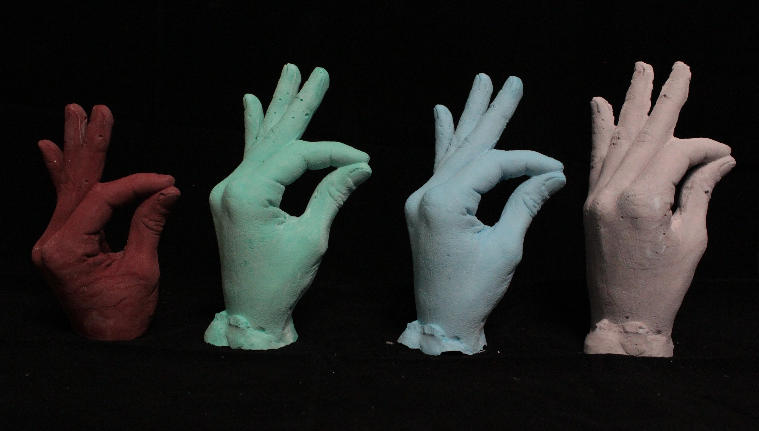 four lifecasts of female hand pigmented: red, green, blue, lavendar
