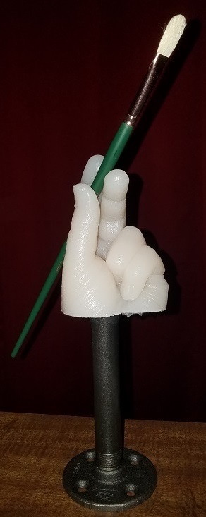 cast hand on stand holding artist paint brush