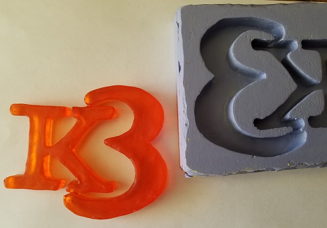 orange Logo removed from mold and placed next to mold