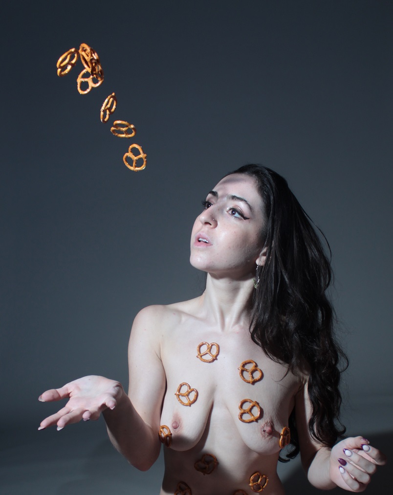 Nude model tossing pretzels in the air