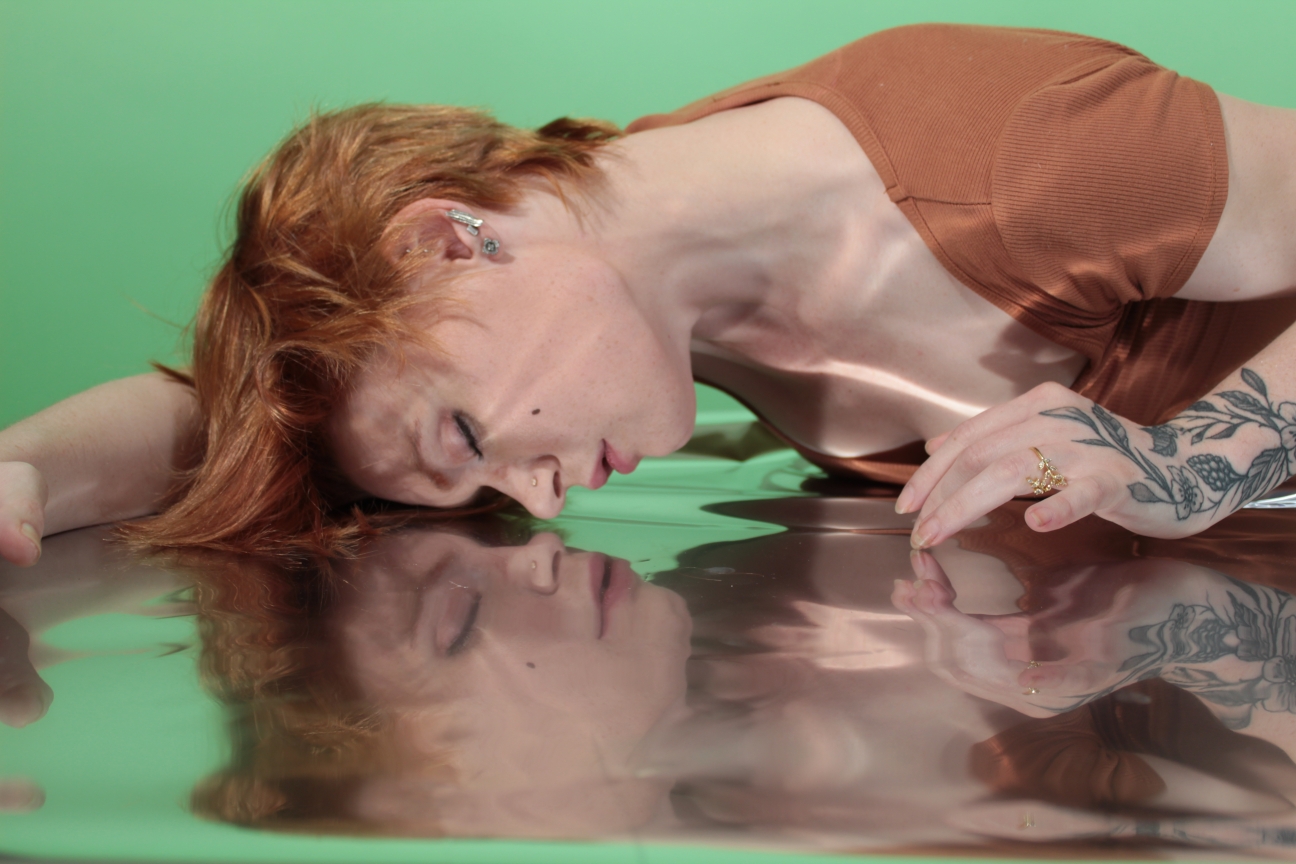 Model in brown dress laying on mylar covered table