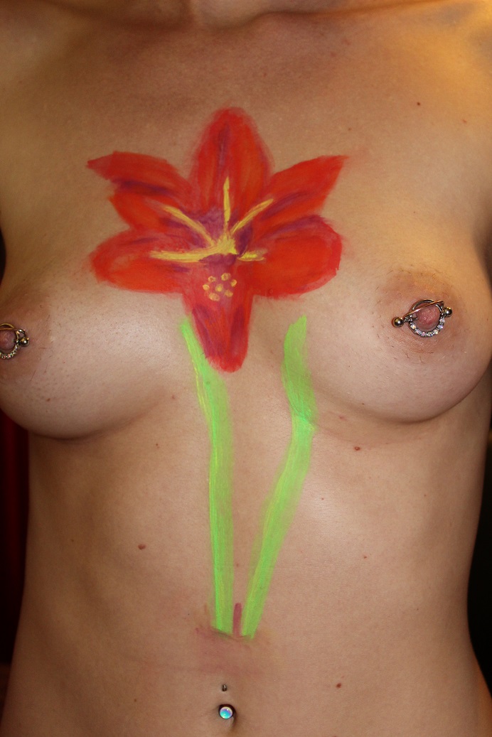 body painting of Red Lion flower done in U V body paint on female torso seen in daylight