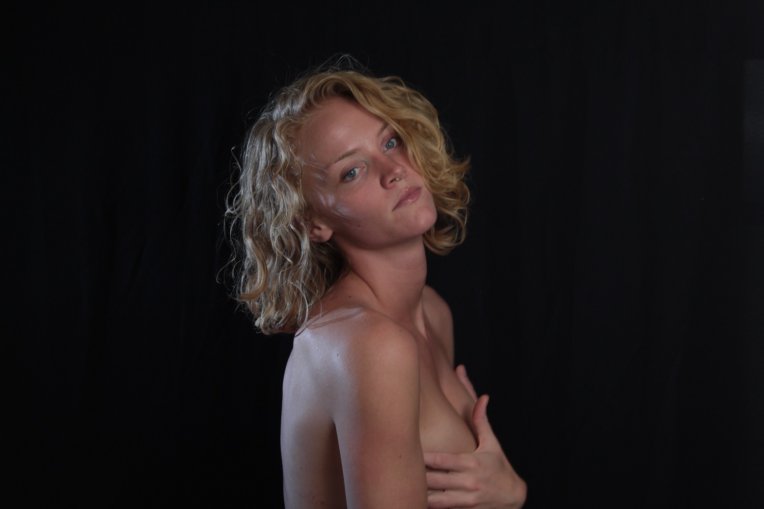 Photo of Kay, implied nude pose, in front of a backdrop