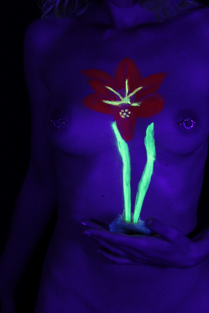 body painting of Red Lion flower done in U V body paint on female torso seen in U V light