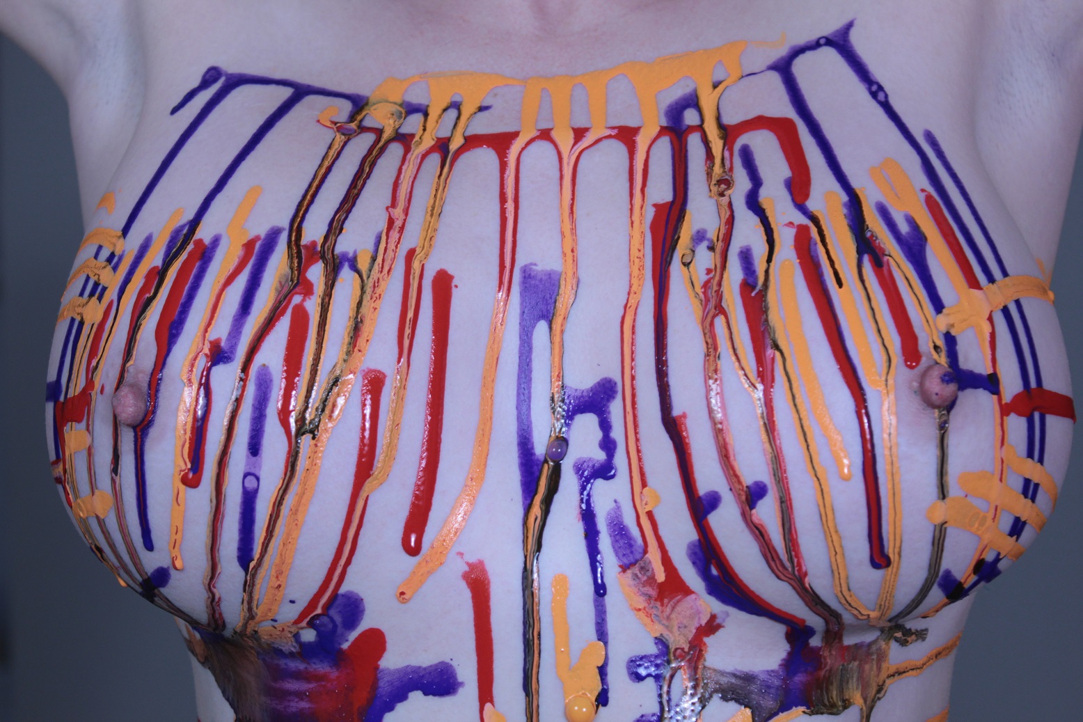 Orange, Blue and Red body paint dripping on female torso