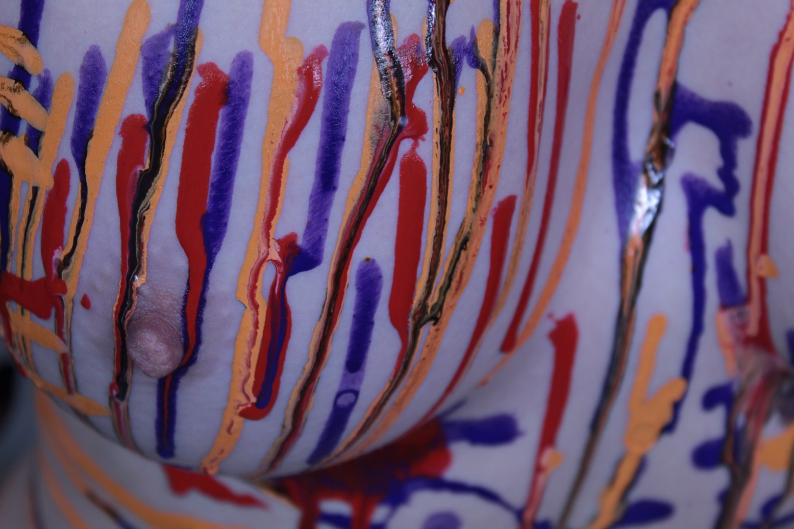 Orange, Blue and Red body paint dripping on female torso
