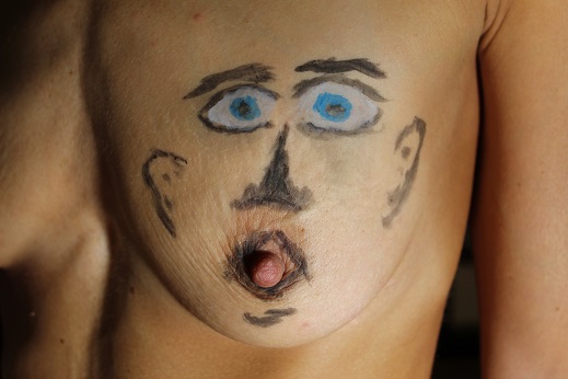 painting on right breast of a face where the nipple is the tongue sticking out